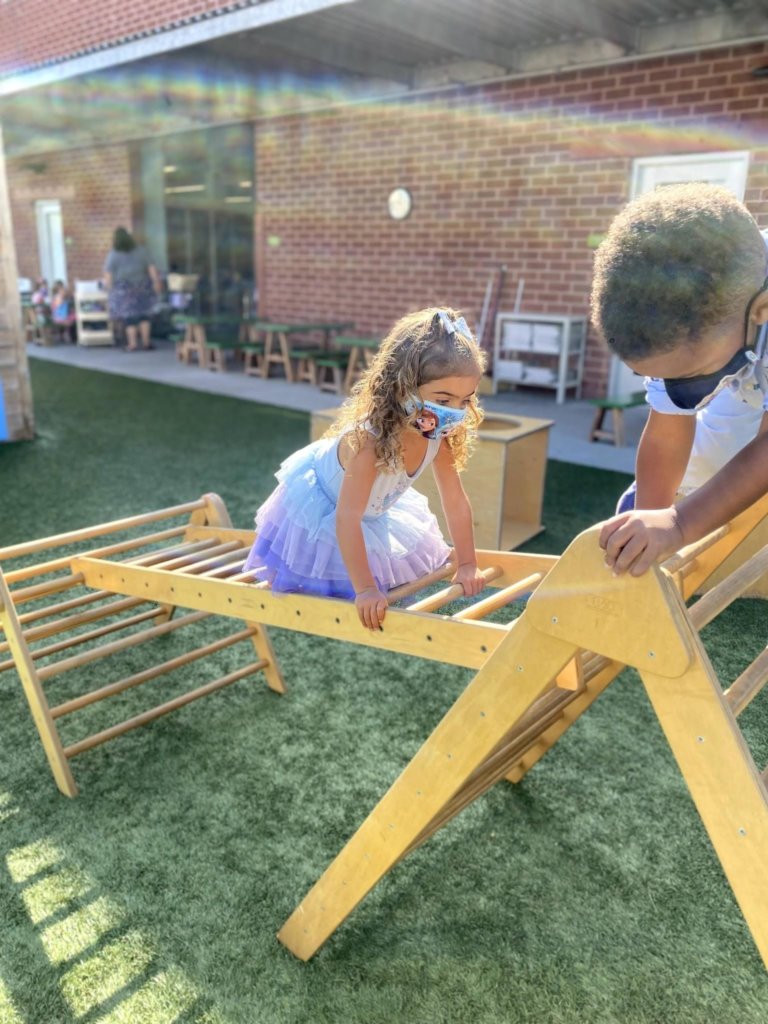 Two children climbing on an outdoor play structure at the Early Childhood Center